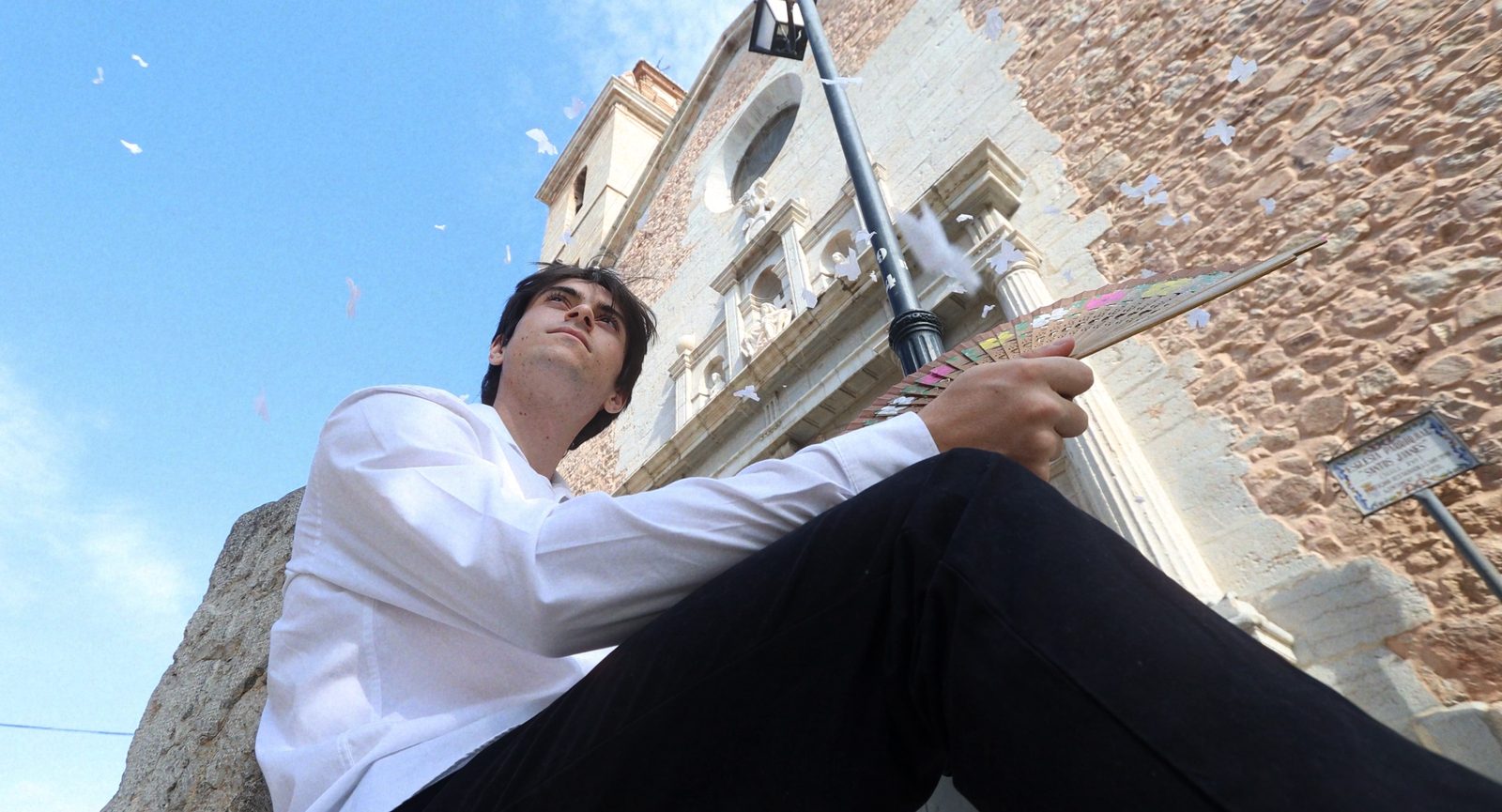 El poeta a los pies de la iglesia con palomas de papel